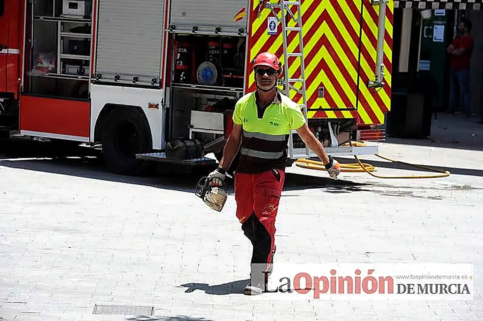Víctor Arce Vicente con motosierra y equipo de trepa junto a un camión de bomberos, tras un trabajo de corte de arbolado